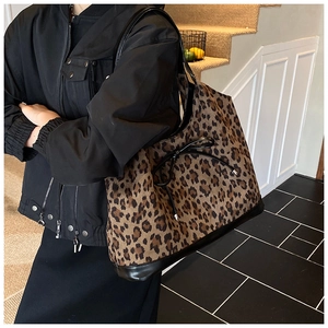 Detail of large leopard print tote bag with black leather trim and bow decoration