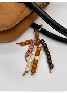 Detail of beaded bag charms with wooden beads in mixed tones on a premium handbag