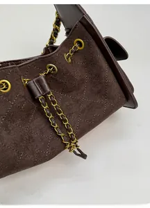 Close-up of quilted suede shoulder bag showing metal eyelets and chain drawstring detail