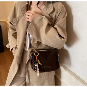 Détail du sac bandoulière en cuir dépoli marron foncé avec gland perlé et boucle dorée