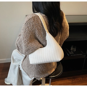 Dettaglio della trama intrecciata bianca su una borsa a spalla minimalista a mezzaluna