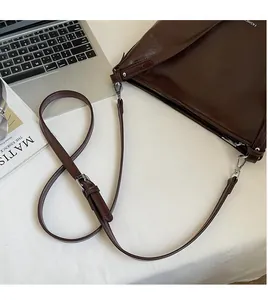 Détail de la bandoulière réglable et de la boucle en métal argenté du sac en cuir
