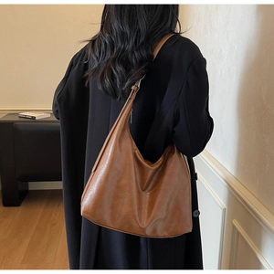 Rear view of a model wearing the large brown leather hobo bag in a minimalist room