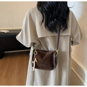 Close-up of deep brown suede handbag with decorative wooden beads on a khaki trench coat