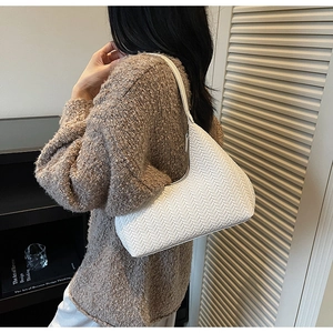 Dettaglio della trama intrecciata bianca su una borsa hobo indossata da una modella