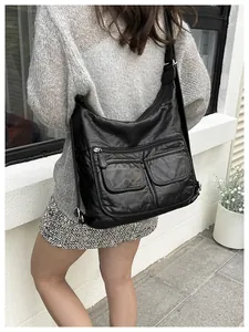 Close-up of black multifunctional crossbody bag with soft wrinkled leather texture and pockets