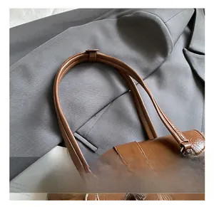 Detail showing the brown faux leather texture and silver metal clasp of the handbag