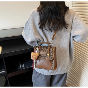 Crossbody bag with leopard print flap and cute bear pendant shown on shoulder
