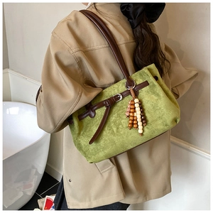 Detail of green suede tote bag with brown leather trim and decorative wooden beads