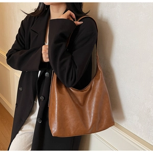 Detail of vintage brown leather tote bag with soft texture and wide shoulder strap