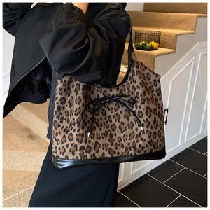 Detailed view of leopard print tote bag with black leather trim and bow knot detail
