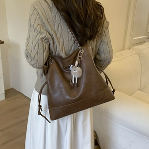 Détail du grand sac cabas marron avec bandoulière chaîne et breloque en peluche beige