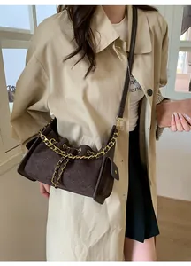 Close-up of dark brown quilted suede bag with gold chain and refined stitching detail