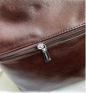 Détail du zip en métal argenté sur un sac seau vintage en cuir marron texturé