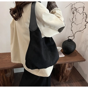 Close-up of minimalist black suede tote bag showing soft texture and leather strap details
