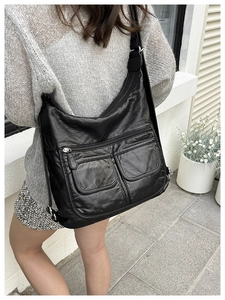 Detail of black soft leather shoulder bag showing functional multi-layer silver zippers