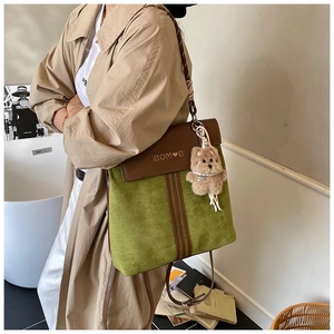 Detail of green suede backpack with brown leather flap and cute bear pendant on a model