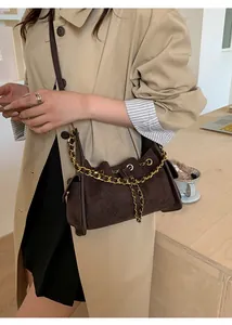 Close-up of quilted suede shoulder bag in dark brown with decorative gold chain strap