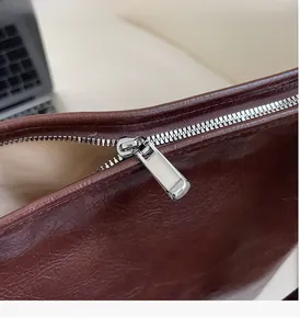 Détails de la fermeture éclair argentée et cuir marron huilé d'un sac bandoulière rétro