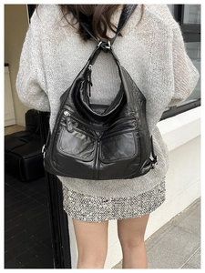 Detail view of large black multi-pocket leather backpack on model for travel use
