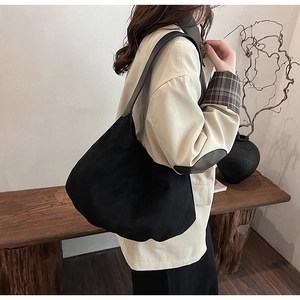 Macro view of large black hobo tote bag with matte texture on a model shoulder