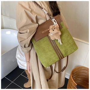 Close-up of green suede backpack with brown leather flap and cute bear pendant