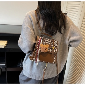 Detail of retro small backpack in brown leather and leopard print with scarf and bear charm