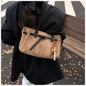 Brown suede tote bag detail featuring black leather strap and wooden bead charm accent