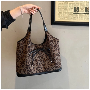 Detailed macro view of the leopard print fabric and black leather trim on this tote bag