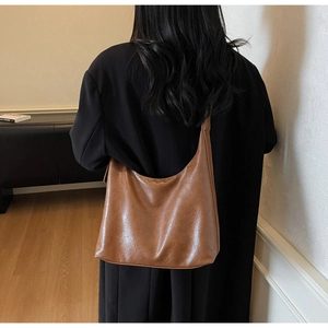 Brown oil wax leather tote bag shown in a lifestyle commuter scene with large capacity