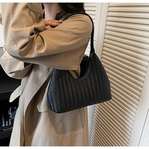 Dettaglio di una borsa hobo intrecciata nera indossata da una modella in trench beige