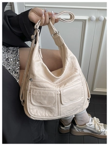 Detail view of beige multi-pocket travel handbag with soft pebbled faux leather texture