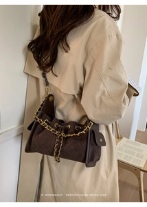 Detail of dark brown suede bucket bag with quilted patterns and golden chain strap