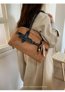 Brown suede handbag with black leather straps and wooden bead tassel in a retro style
