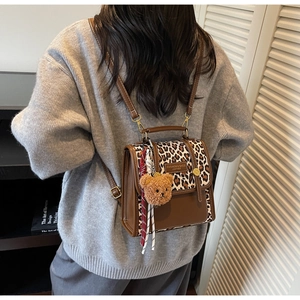 Detail of small brown leather backpack with leopard print flap and cute bear pendant charm