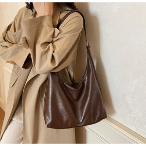 Detail of dark brown hobo bag with pebble leather texture on a beige coat outfit