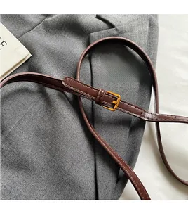 Detail of adjustable brown faux leather shoulder strap with gold metal buckle for bags