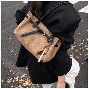 Close-up of brown suede tote bag with wooden bead pendant and black leather ties
