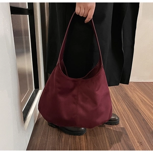 Detail view of burgundy crescent nylon tote bag with smooth satin finish texture