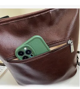 Gros plan d'un cabas en cuir marron foncé montrant la poche arrière zippée pratique