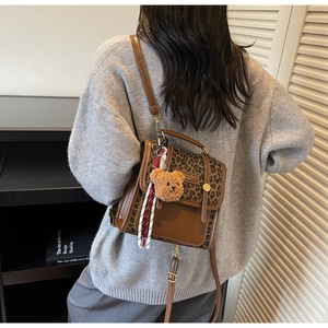 Brown leopard patchwork messenger bag with bear charm shown on a casual model