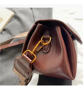 Detail view of vintage brown bag with glossy metal hook and wide woven shoulder strap