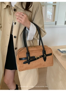 Close-up of brown suede Boston bag with black leather handles and gold horsebit hardware