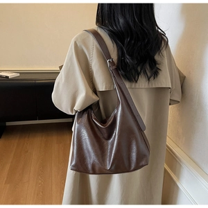 Detailed shot of dark brown hobo bag showing the glossy leather texture and metal buckle