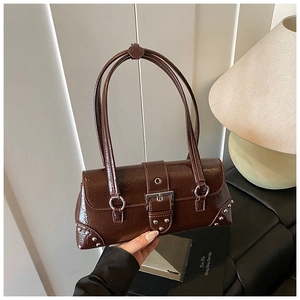 Close-up of retro brown glossy leather pillow bag with silver studs and metal buckle detail