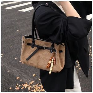 Brown faux suede tote bag featuring black leather straps and a colorful beaded tassel charm