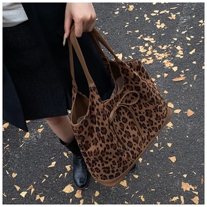 Detailed shot of leopard print tote bag with brown handles and bow on autumn street