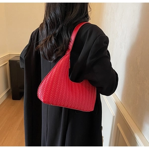 Dettaglio della trama intrecciata rossa di una borsa a mezzaluna su un blazer nero