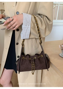 Détail d'un sac à main rétro en daim marron avec chaîne dorée sur un trench-coat