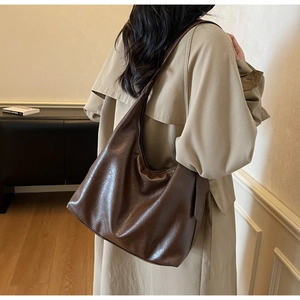 Brown vintage faux leather tote bag shown on a model in a cozy indoor setting